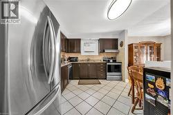 Stainless steel appliances complement the dark wood cabinetry in this kitchen featuring an integrated sink, patterned tile backsplash, and overhead lighting - 
