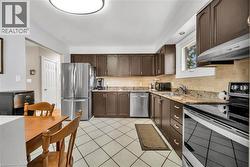 Kitchen featuring dark wood cabinetry, stainless steel appliances, a tile backsplash - 