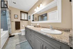 Bathroom featuring a double vanity with stone-finish countertop, dual sinks, and gray cabinetry - 