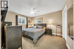 Carpeted room featuring a ceiling fan with integrated lighting, a window with dark drapes, and neutral-toned wall paint - 