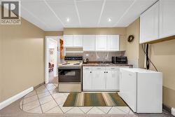 Kitchenette featuring white cabinetry, a neutral tiled backsplash, a brown countertop, and recessed lighting - 