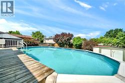 Expansive above-ground swimming pool featuring entry steps and an adjacent wood deck - 