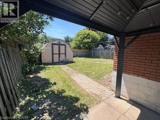 Expansive backyard featuring a storage shed, a brick patio section, and a paved walkway - 90 Anna Capri Drive Unit# Lower, Hamilton, ON - Outdoor With Exterior