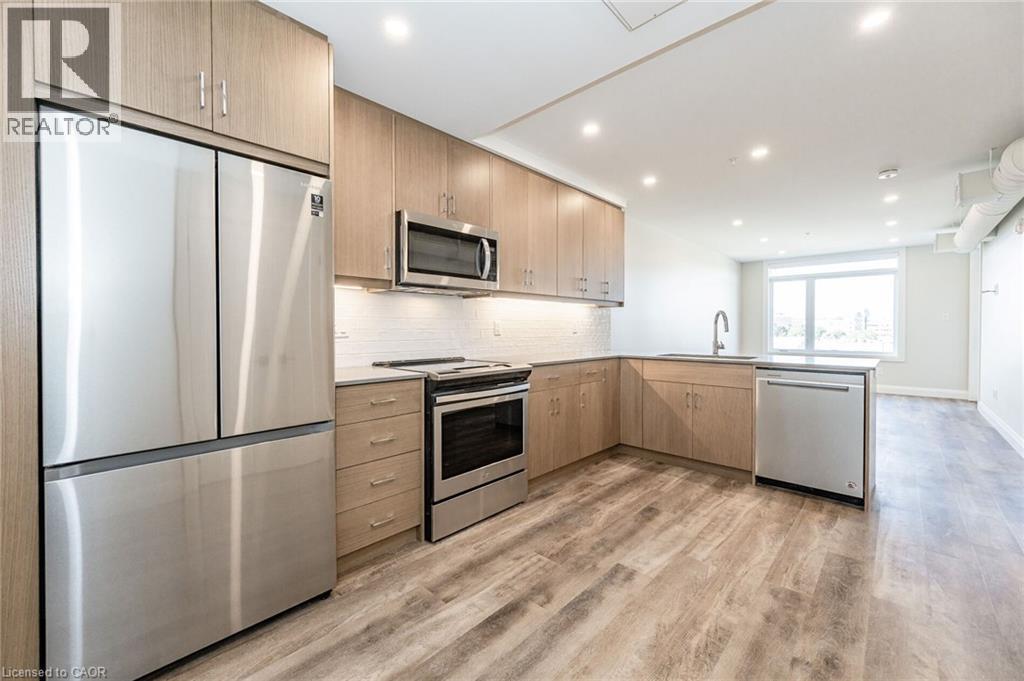 Kitchen featuring wood-finish cabinetry, stainless steel appliances, white subway tile backsplash, and recessed lighting - 72 Erb Street E Unit# 102, Waterloo, ON - Indoor Photo Showing Kitchen With Upgraded Kitchen