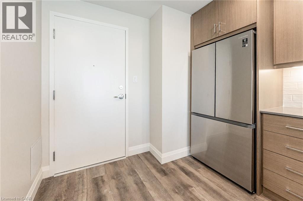 Modern stainless steel refrigerator integrated into wood-finish cabinetry - 72 Erb Street E Unit# 102, Waterloo, ON - Indoor
