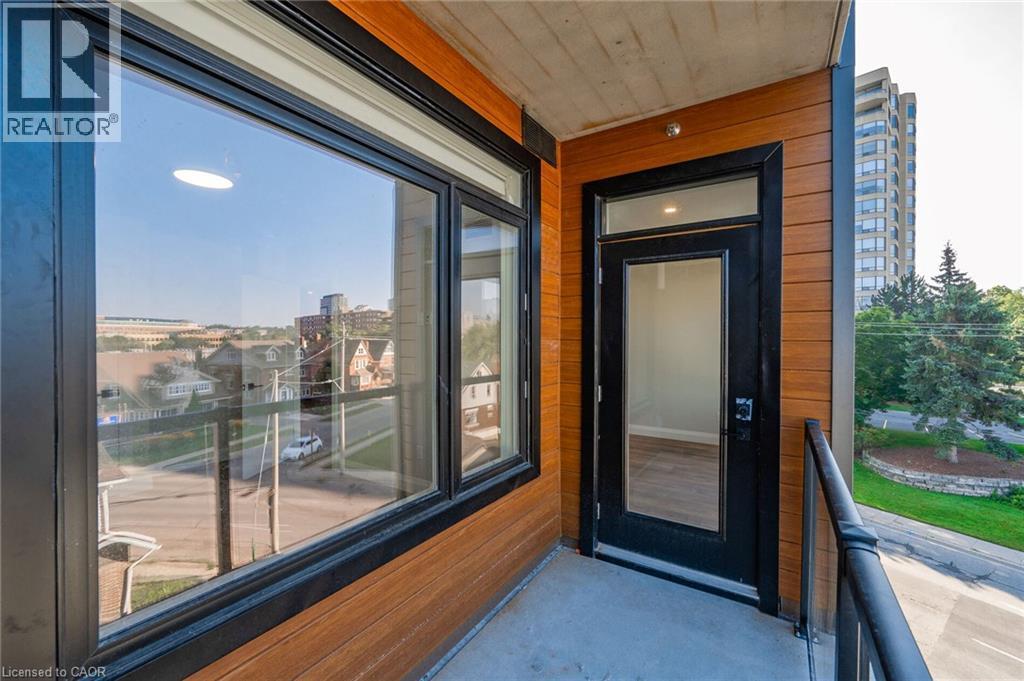 Balcony featuring wood-look siding, dark-framed windows, and a glass-paneled door - 72 Erb Street E Unit# 102, Waterloo, ON - Outdoor With Balcony With Exterior