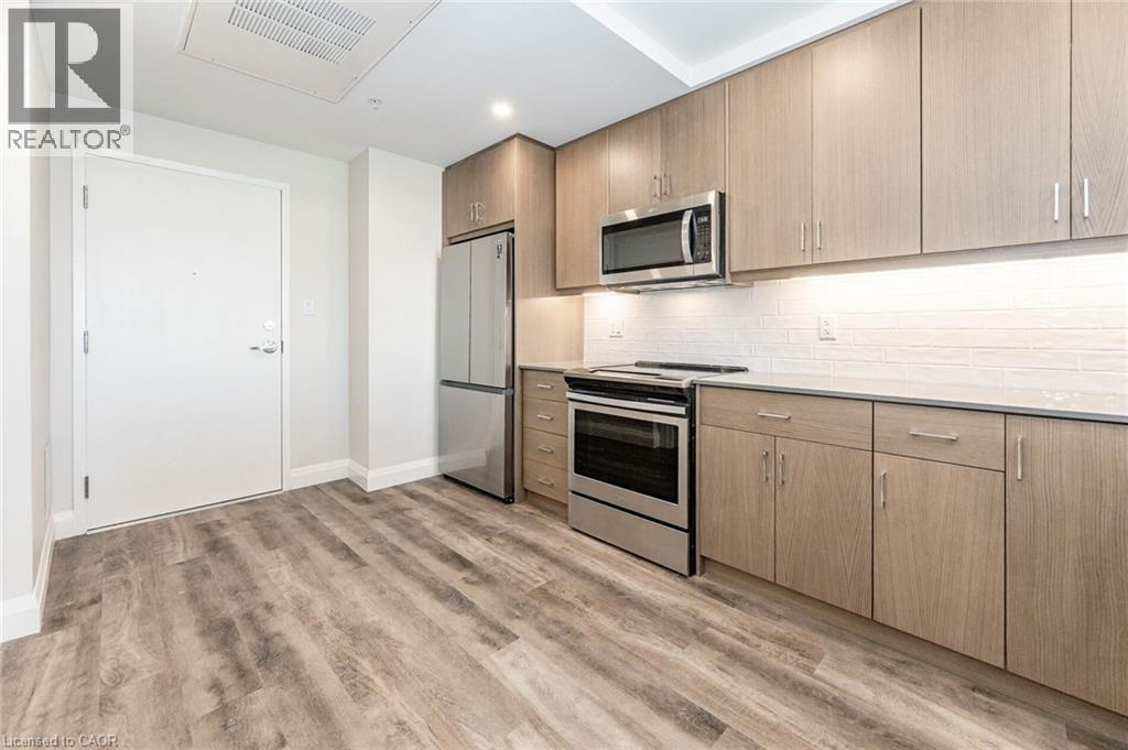 Modern kitchen featuring wood-finish cabinetry, stainless steel appliances, and wood-finish flooring - 72 Erb Street E Unit# 102, Waterloo, ON - Indoor Photo Showing Kitchen