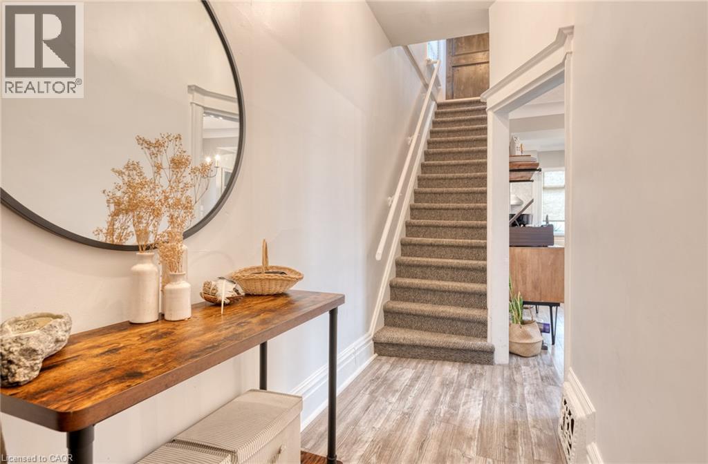 Entryway featuring wood-finish flooring, a carpeted staircase with white handrail, and white wall molding - 37 Cliff Avenue Unit# Upper, Hamilton, ON - Indoor Photo Showing Other Room