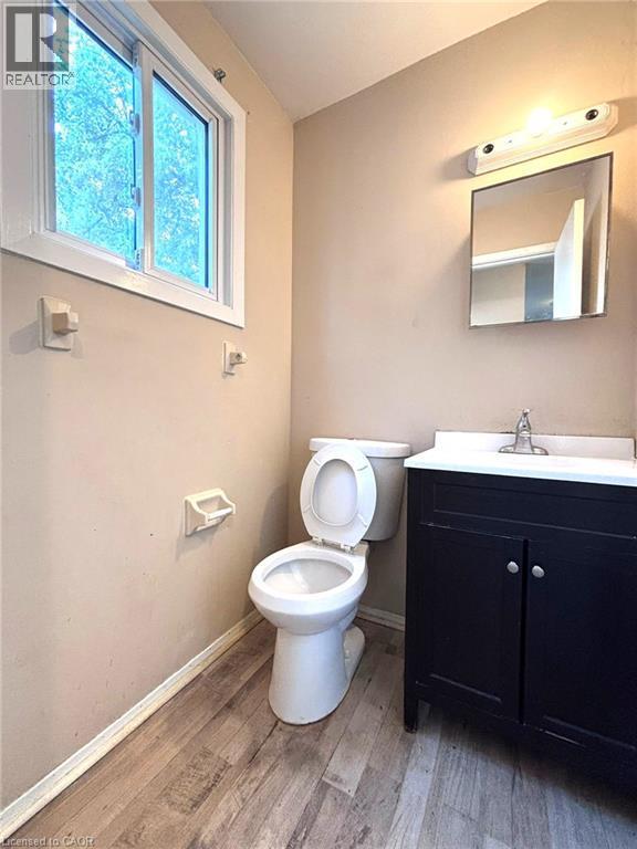 Bathroom featuring a window, wood-finish flooring, and a dark vanity with a white countertop - 490 Third Street Unit# 40, London, ON - Indoor Photo Showing Bathroom