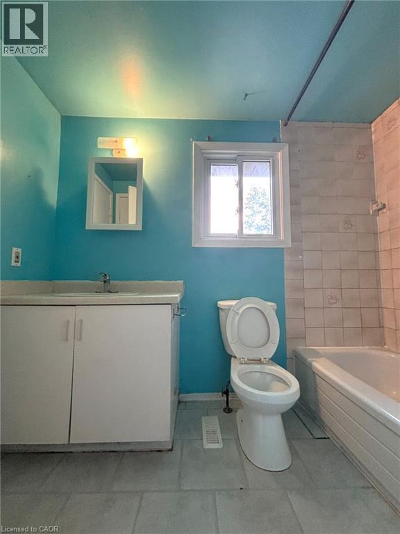 Bathroom with a single vanity, a toilet, and a bathtub with tiled surround - 490 Third Street Unit# 40, London, ON - Indoor Photo Showing Bathroom