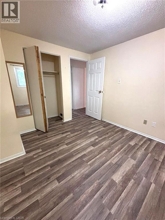 Interior room featuring wood-finish flooring, light neutral-toned walls, and a white six-panel door - 490 Third Street Unit# 40, London, ON - Indoor Photo Showing Other Room