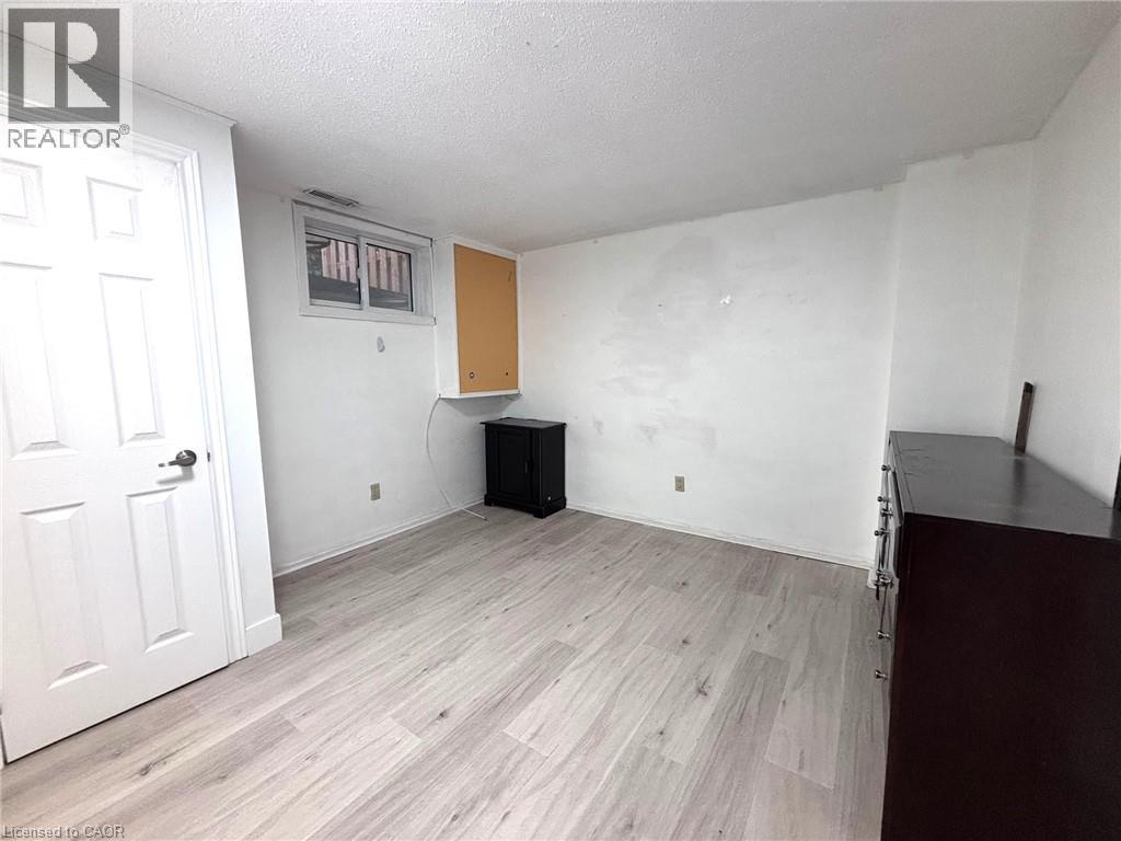 Spacious room featuring light wood-finish flooring, white painted walls, a standard white door, and a horizontal window - 490 Third Street Unit# 40, London, ON - Indoor Photo Showing Other Room