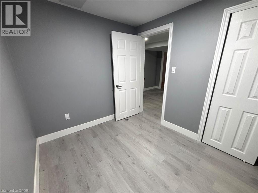 Room featuring light wood-finish flooring, grey painted walls, white trim, and white paneled doors - 490 Third Street Unit# 40, London, ON - Indoor Photo Showing Other Room