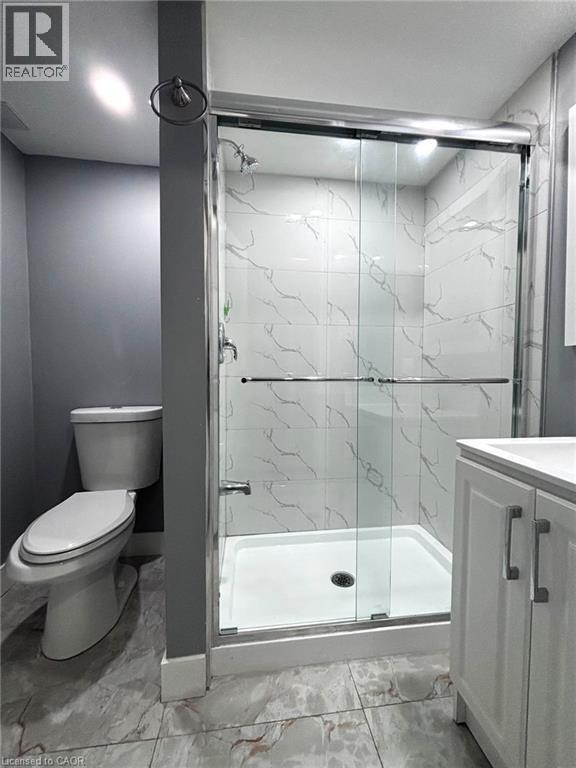 Bathroom featuring a walk-in shower with clear glass sliding doors, a white shower pan, and white wall tiles with veining - 490 Third Street Unit# 40, London, ON - Indoor Photo Showing Bathroom