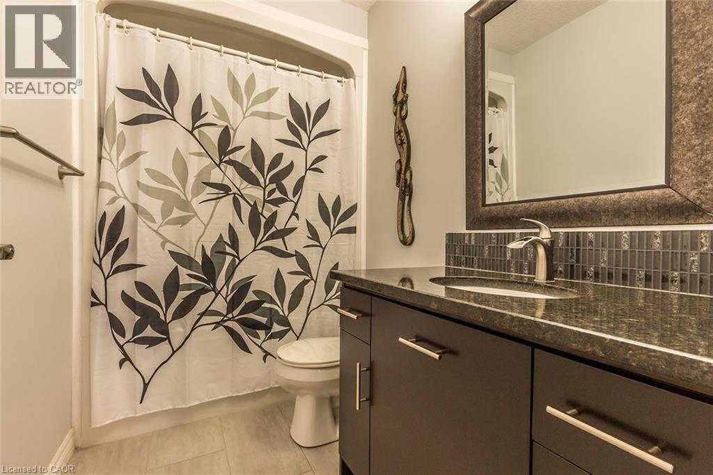 Vanity featuring a dark countertop, undermount sink, and brushed nickel faucet - 44 Lemon Grass Street, Kitchener, ON - Indoor Photo Showing Bathroom