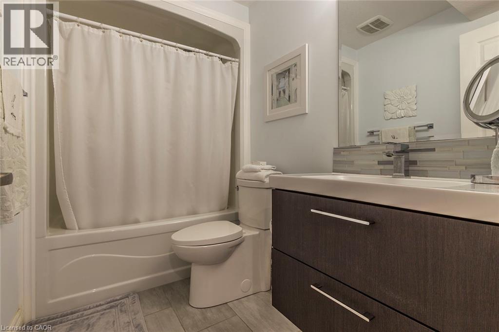 Bathroom featuring a white bathtub with shower, wood-finish vanity with two drawers, and a white integrated sink - 44 Lemon Grass Street, Kitchener, ON - Indoor Photo Showing Bathroom