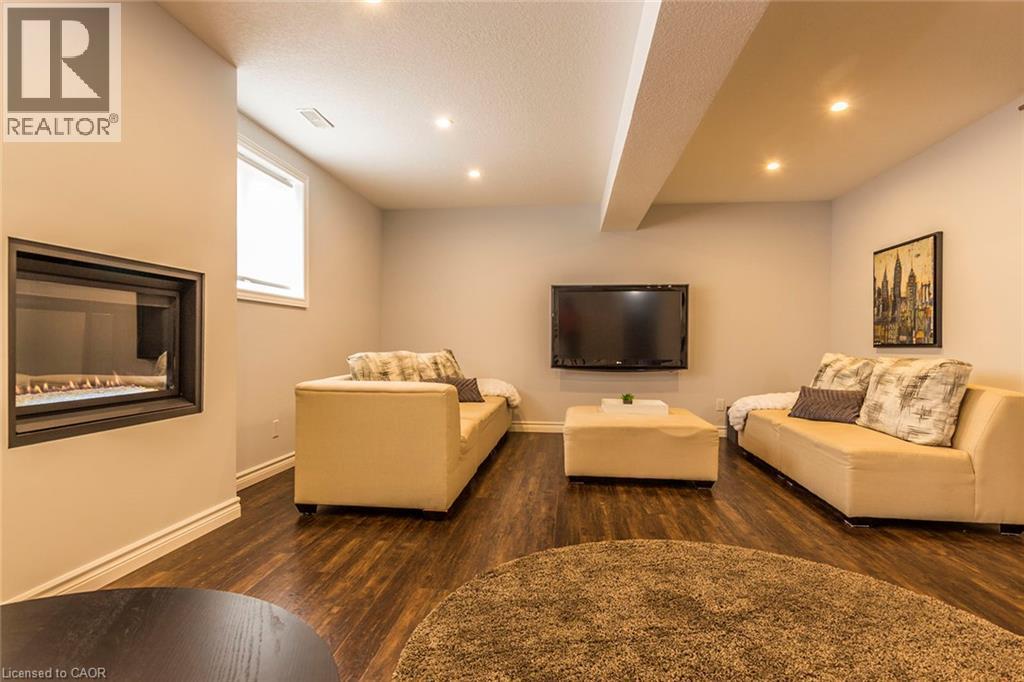 Recessed fireplace with a dark surround, wood-finish flooring, and recessed ceiling lighting - 44 Lemon Grass Street, Kitchener, ON - Indoor