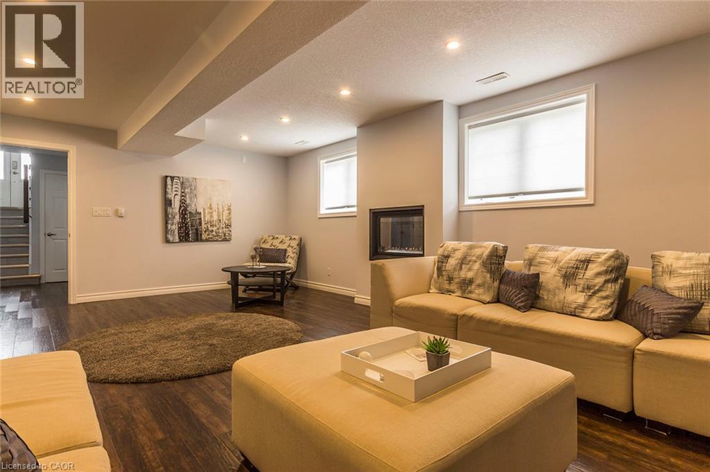 Recreation room featuring recessed lighting, wood-finish flooring, a built-in electric fireplace, and two windows with blinds - 44 Lemon Grass Street, Kitchener, ON - Indoor Photo Showing Living Room