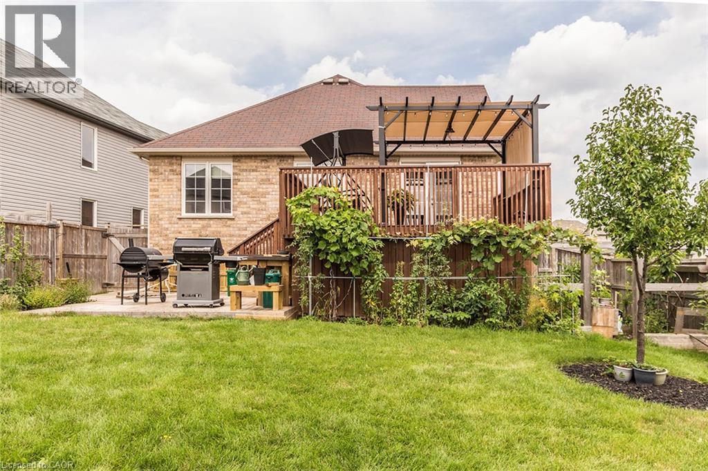 Expansive rear yard featuring a wooden deck with railing, a pergola with a retractable canopy, and a concrete patio - 44 Lemon Grass Street, Kitchener, ON - Outdoor With Deck Patio Veranda