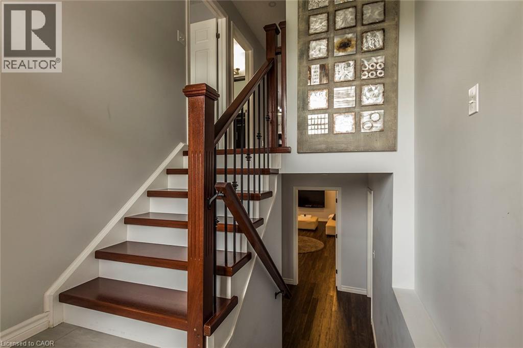 Staircase featuring dark wood-finish treads, white risers, and a dark wood newel post with black metal balusters - 44 Lemon Grass Street, Kitchener, ON - Indoor Photo Showing Other Room