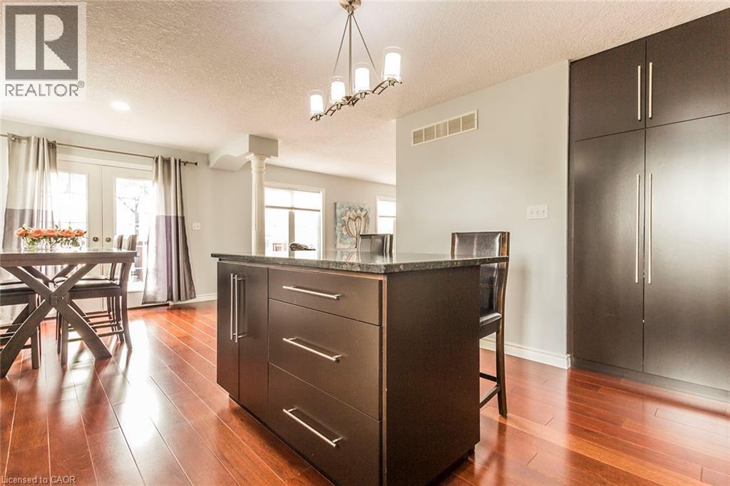 Kitchen island featuring a dark countertop, integrated storage, and bar seating - 44 Lemon Grass Street, Kitchener, ON - Indoor