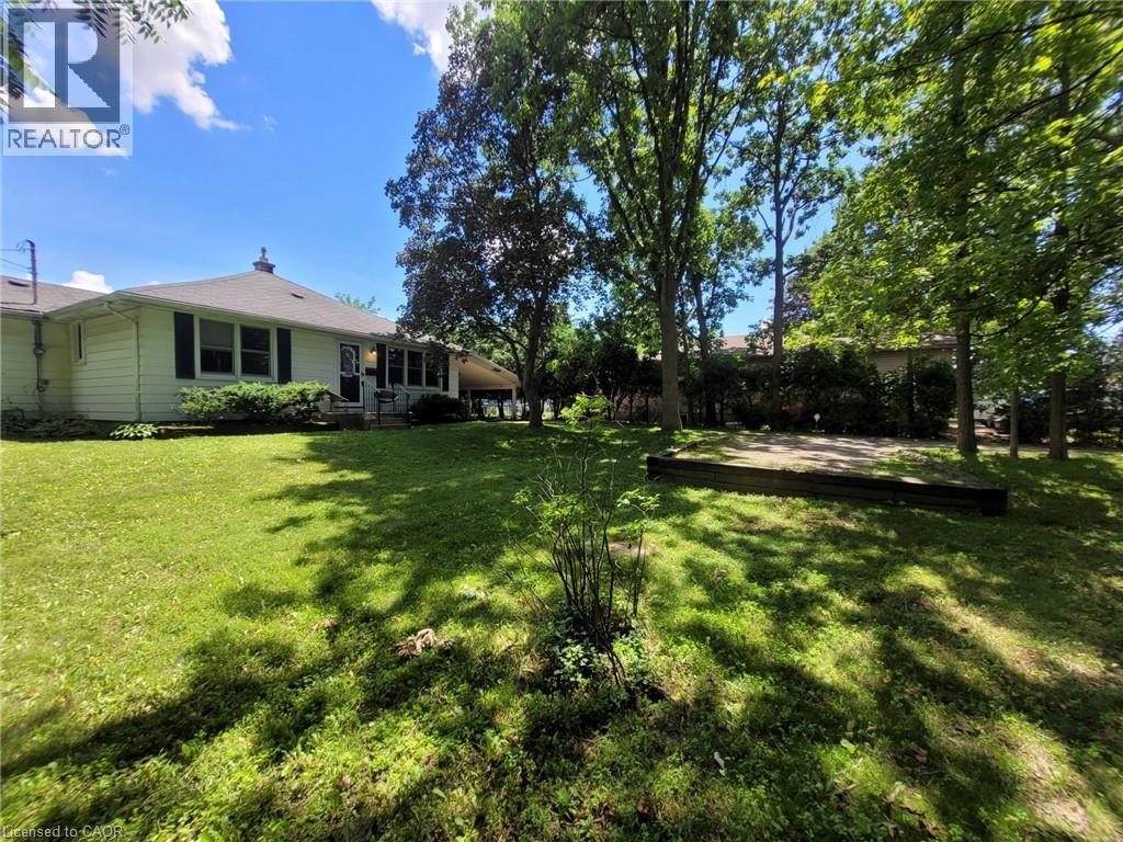 Expansive green space featuring a level lawn, mature trees providing natural shade, and a raised garden bed - 879 West 5Th Street, Hamilton, ON - Outdoor
