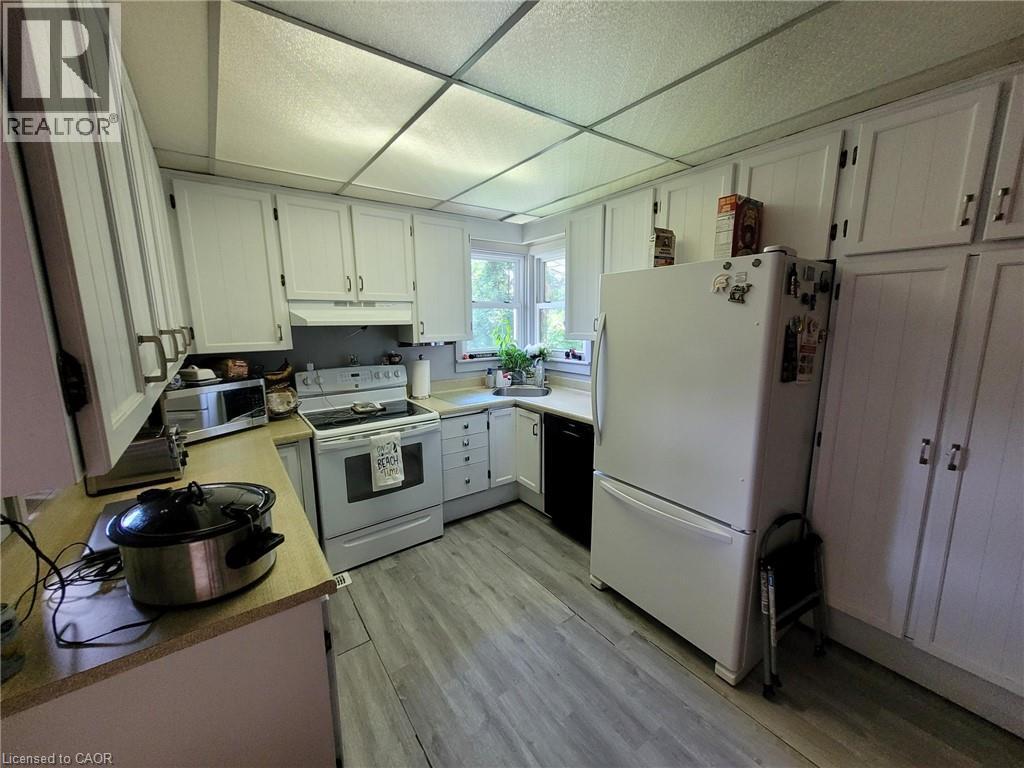 Kitchen featuring white cabinetry, light wood-finish countertops, stainless steel sink, and wood-finish flooring - 879 West 5Th Street, Hamilton, ON - Indoor Photo Showing Kitchen