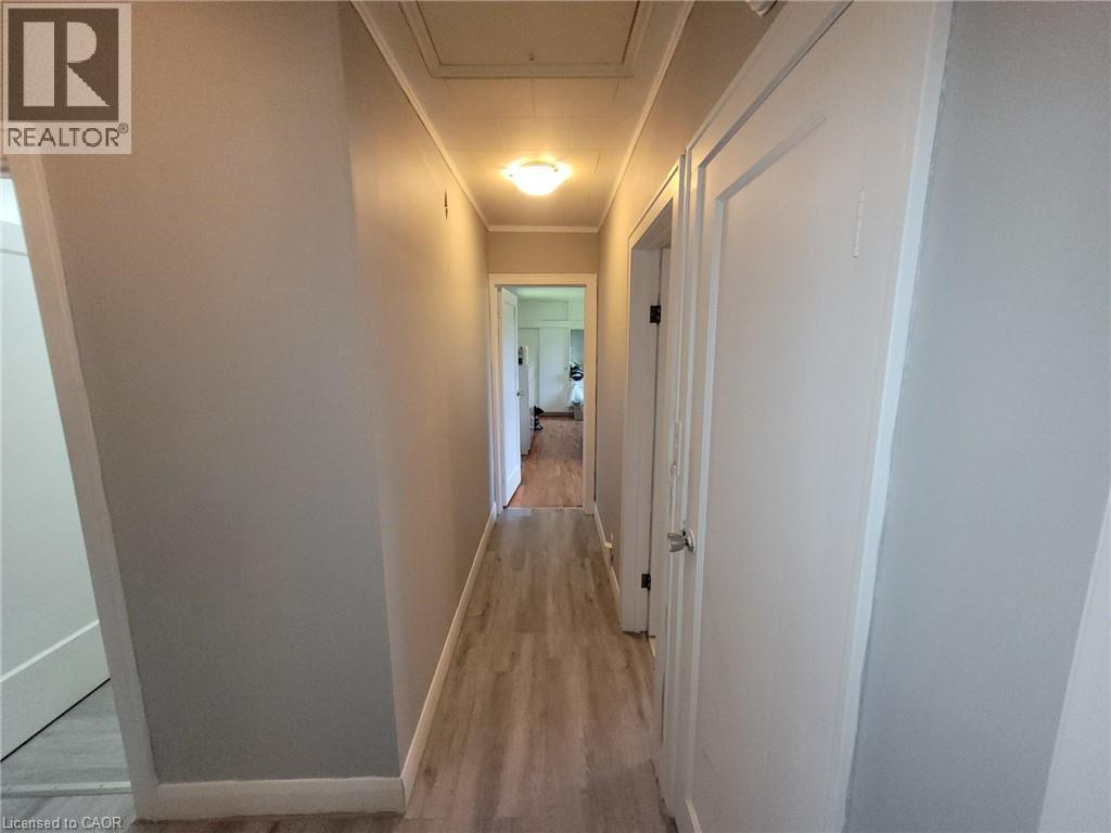 Hallway with wood-finish flooring, light gray wall paint, white trim, and a flush-mount ceiling light fixture - 879 West 5Th Street, Hamilton, ON - Indoor Photo Showing Other Room