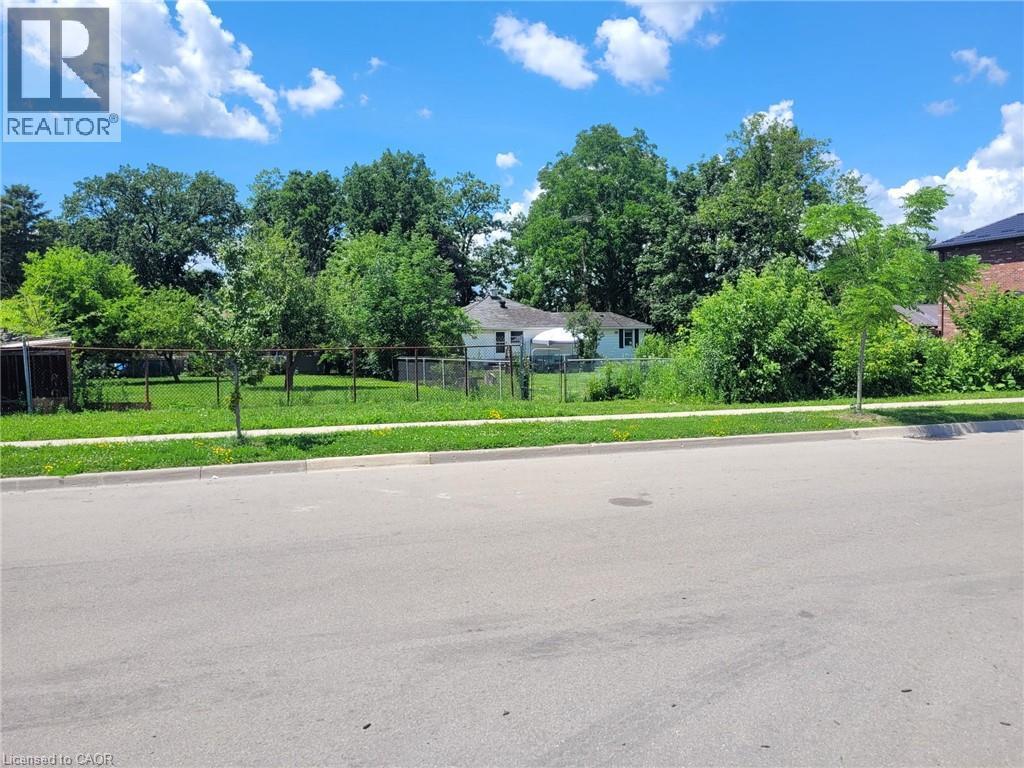 Expansive green space featuring a chain-link fence, mature trees, and a visible sidewalk - 879 West 5Th Street, Hamilton, ON - Outdoor