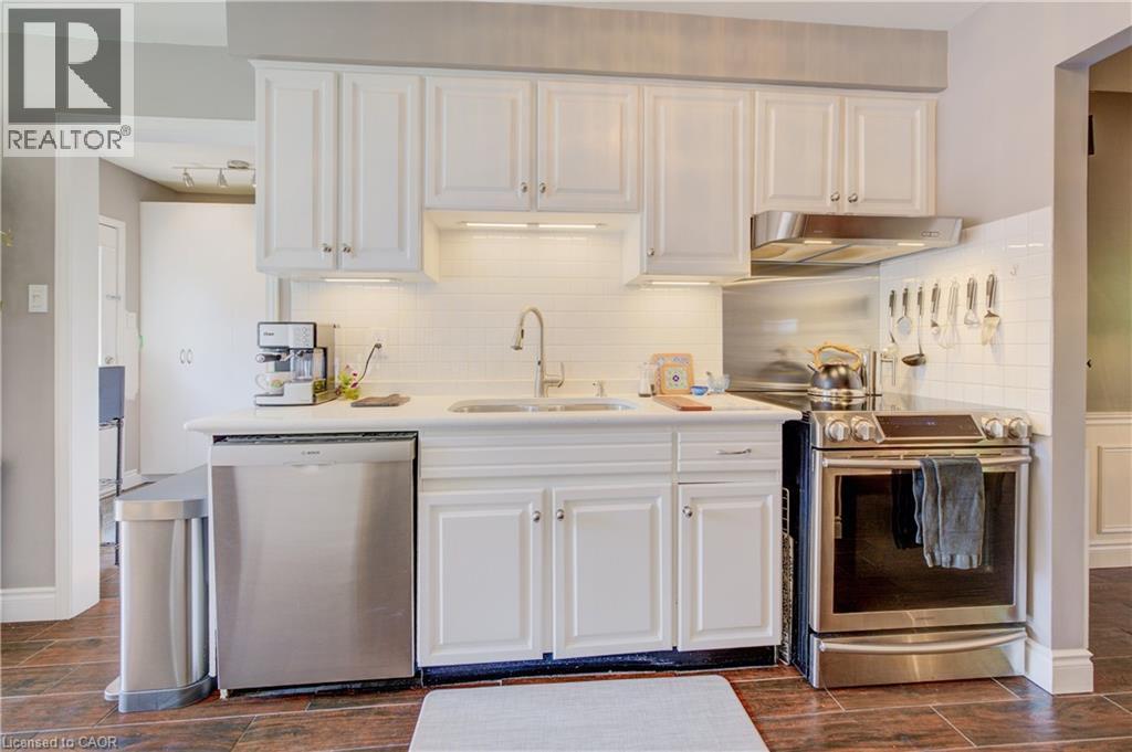 Kitchen showcasing white cabinetry, stainless steel appliances, white subway tile backsplash, and wood-finish flooring - 41 Mcniven Road, Ancaster, ON - Indoor Photo Showing Kitchen With Upgraded Kitchen
