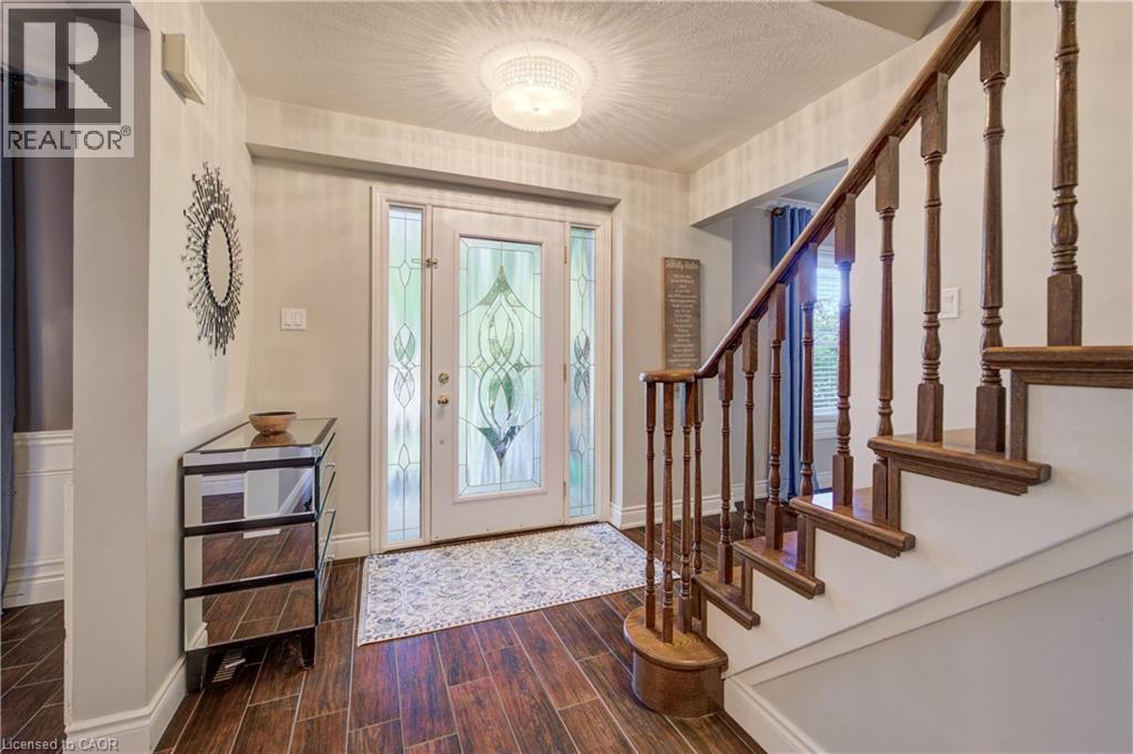 Foyer featuring wood-finish flooring, a decorative front entry door with privacy glass, an overhead flush-mount light fixture, and a staircase with wood balusters and handrail - 41 Mcniven Road, Ancaster, ON - Indoor Photo Showing Other Room