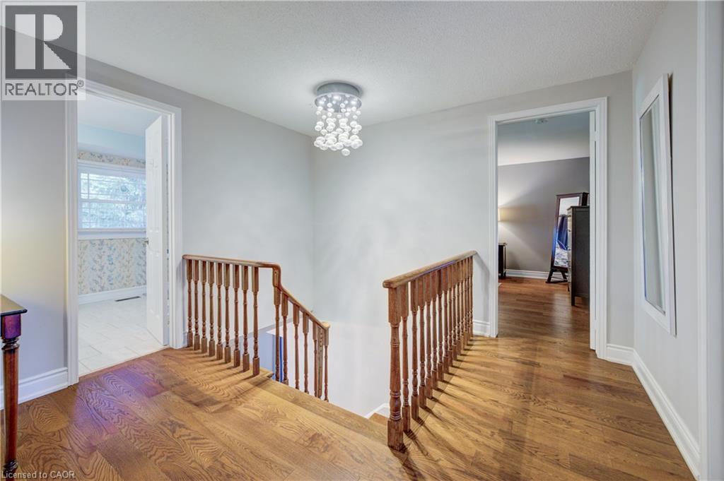 Hallway with wood-finish flooring, white trim, and a contemporary ceiling light fixture - 41 Mcniven Road, Ancaster, ON - Indoor Photo Showing Other Room
