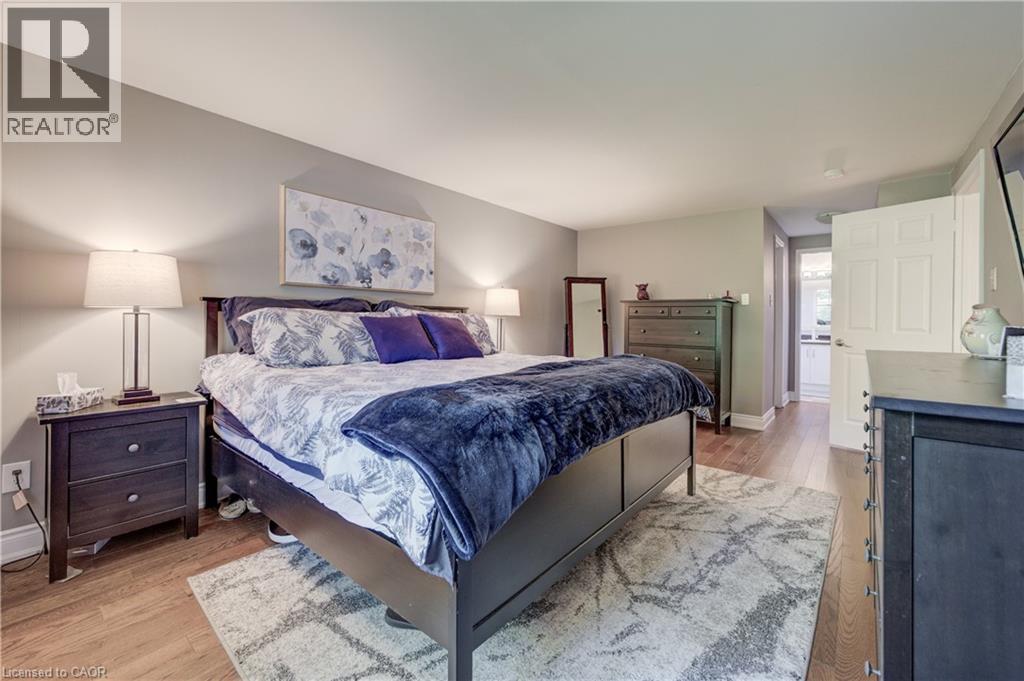 Spacious bedroom featuring wood-finish flooring, light grey wall paint, and white trim - 41 Mcniven Road, Ancaster, ON - Indoor Photo Showing Bedroom