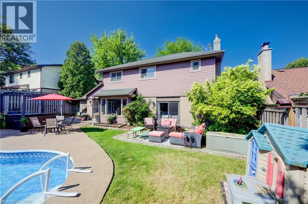 Expansive backyard featuring a concrete patio, an in-ground pool, a green lawn area, and mature landscaping - 41 Mcniven Road, Ancaster, ON - Outdoor With In Ground Pool