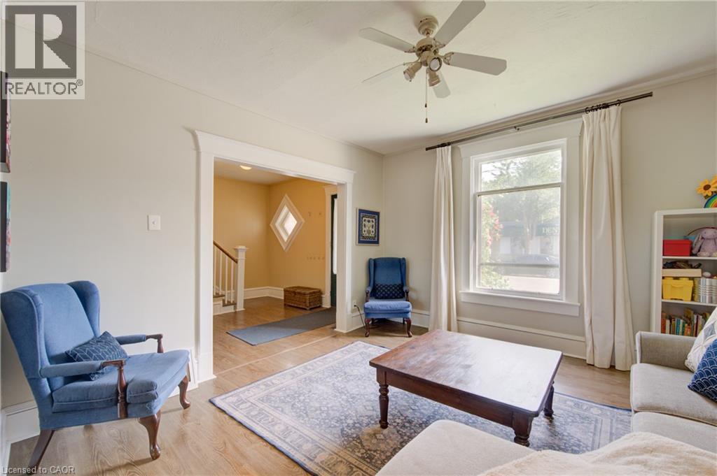 Spacious room featuring wood-finish flooring, a ceiling fan, and a large window with white trim - 39 Kerr Street, Cambridge, ON - Indoor Photo Showing Living Room