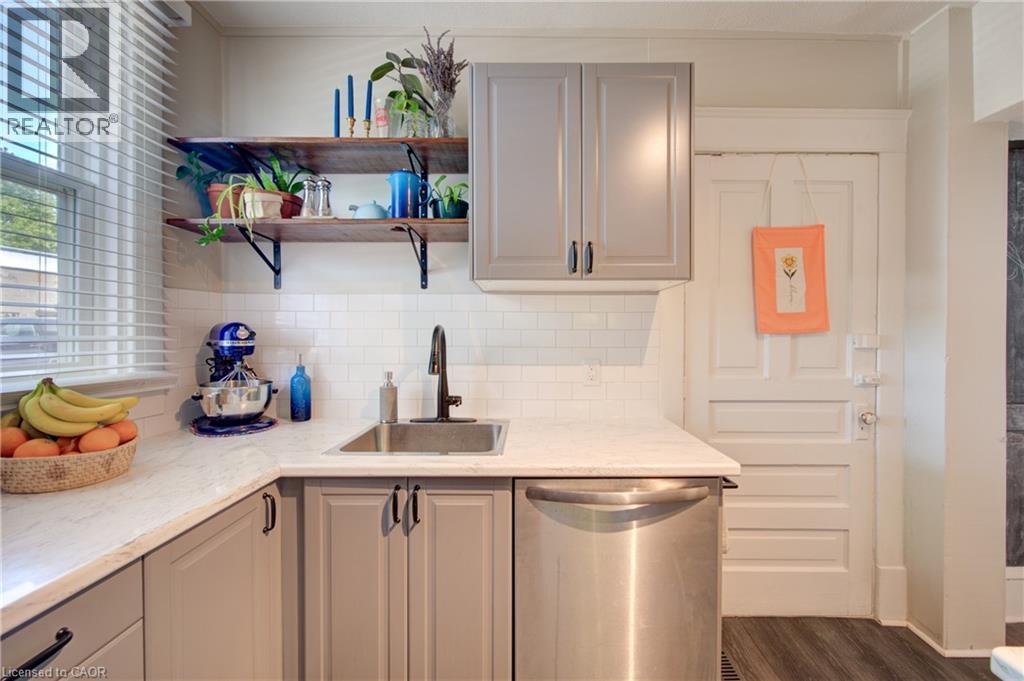 Kitchen workspace featuring light-colored cabinetry, stainless steel dishwasher, a single-basin sink with a matte black faucet, and white subway tile backsplash - 39 Kerr Street, Cambridge, ON - Indoor Photo Showing Kitchen