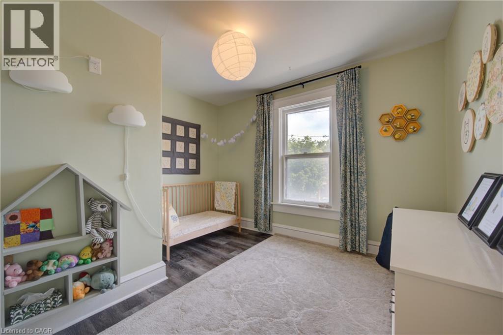 Bedroom with light green walls featuring a single window with drapes, a central ceiling light fixture, and wood-finish flooring - 39 Kerr Street, Cambridge, ON - Indoor