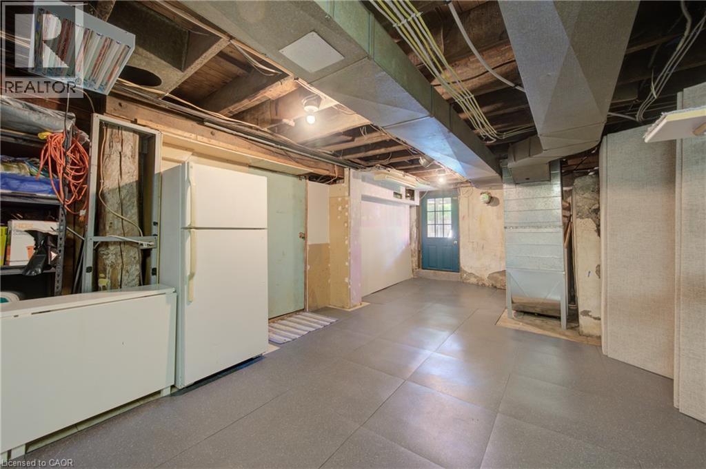 Finished basement space featuring exposed ceiling joists, overhead lighting, an exterior door with glass panes, and a concrete foundation wall - 39 Kerr Street, Cambridge, ON - Indoor Photo Showing Basement