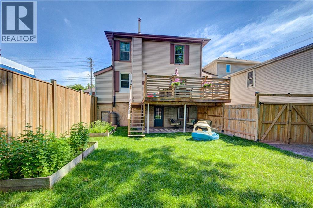 Rear exterior featuring a spacious lawn, a raised wood deck, and a ground-level covered patio - 39 Kerr Street, Cambridge, ON - Outdoor With Deck Patio Veranda