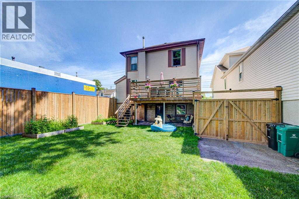 Spacious backyard featuring a manicured lawn, wood privacy fencing, and a multi-level deck with stairs - 39 Kerr Street, Cambridge, ON - Outdoor