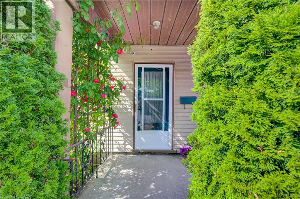 Inviting front entry featuring a white storm door, beige horizontal siding, and a covered porch with wood-finish soffit - 39 Kerr Street, Cambridge, ON - Outdoor