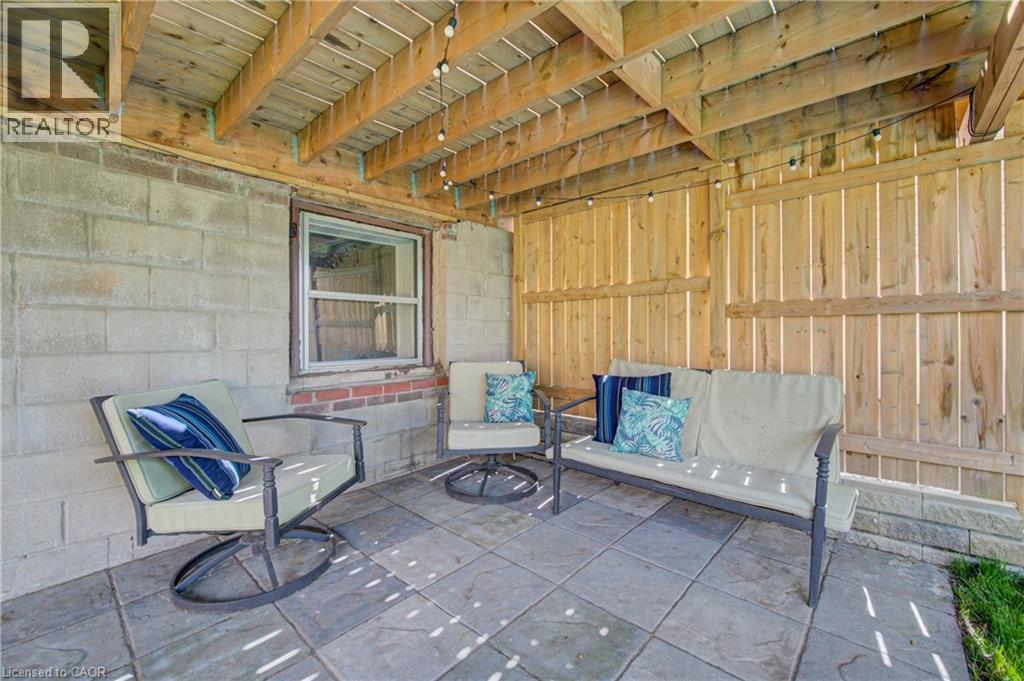 Covered patio featuring a wood ceiling with exposed beams, paver flooring, and a privacy fence - 39 Kerr Street, Cambridge, ON - With Deck Patio Veranda With Exterior