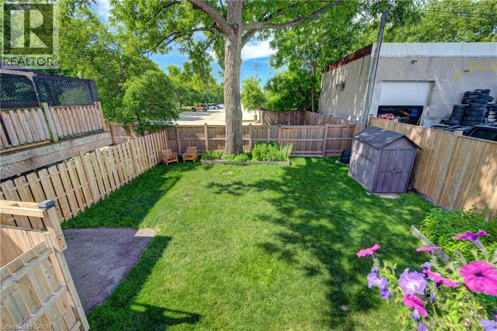 Expansive private yard featuring a substantial natural wood fence, mature shade tree, manicured lawn, and a functional storage shed - 39 Kerr Street, Cambridge, ON - Outdoor