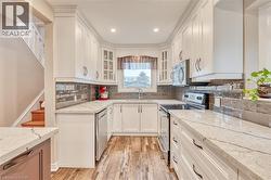 U-shaped kitchen featuring white cabinetry, light-toned countertops, and a dark tile backsplash -