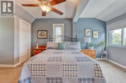Bedroom featuring neutral carpeting, a bi-fold closet door, and a ceiling fan with light fixture -