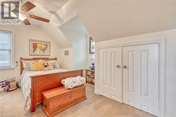 Carpeted room with a ceiling fan, sloped ceilings, and a window with blinds -