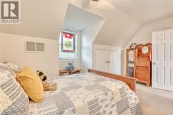 Bedroom featuring a sloped ceiling, carpet flooring, and a window with an artistic glass panel -