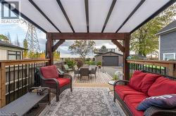Expansive outdoor deck featuring a wooden railing with black balusters, a wood-beam pergola structure, and a translucent panel roof -