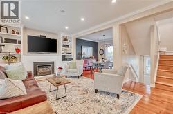 Living area featuring a built-in fireplace, recessed lighting, hardwood flooring, built-in shelving, and crown molding -