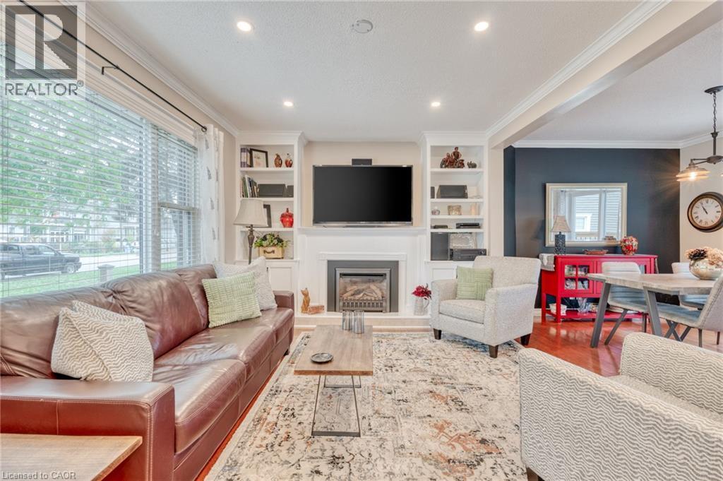 Living room featuring a fireplace with a white mantel, built-in shelving, recessed lighting, hardwood flooring, and crown molding - 851 Beach Boulevard, Hamilton, ON - Indoor Photo Showing Living Room With Fireplace